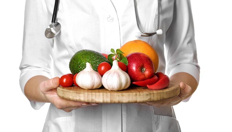 Черновик doctor-holding-wooden-board-with-heart-healthy-foods-on-white-background